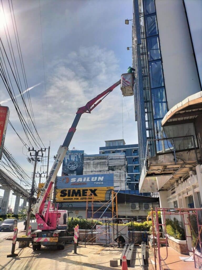 ทีมงานใช้รถกระเช้าบูมข้อพับซ่อมบำรุงไฟภายนอกอาคาร